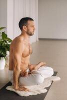 un hombre con un desnudo torso lo hace yoga en un aptitud habitación. el concepto de un sano estilo de vida foto