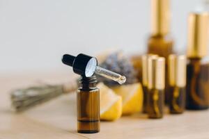 Essential oil in bottles with lemon and lavender fragrance, lying on a wooden surface photo