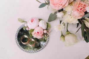 Designer wedding rings lying on the table for the ceremony and decor of roses. Two wedding rings photo