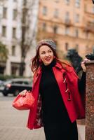 A beautiful stylish woman dressed in an elegant red coat with a stylish red handbag in the autumn city photo