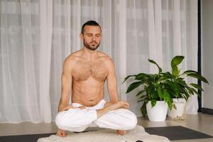 un hombre con un desnudo torso lo hace yoga en un aptitud habitación. el concepto de un sano estilo de vida foto