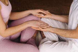 a woman and a man are engaged in pair meditation holding hands in the gym photo