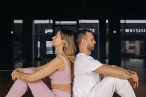 a woman and a man are engaged in pair gymnastics yoga in the gym photo