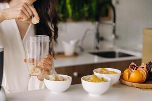 de cerca de el manos de un niña quien hace un desintoxicación cóctel de Fruta en el cocina. dieta para peso pérdida foto