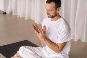 a man in white sportswear is doing yoga with a fitness room. the concept of a healthy lifestyle photo