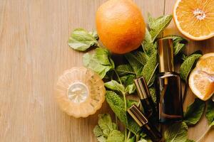 Essential oil in bottles with the aroma of orange and mint lying on a wooden surface photo