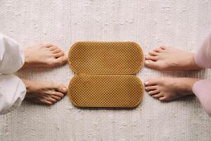 The legs of a man and a woman stand next to boards with nails for Yoga classes photo