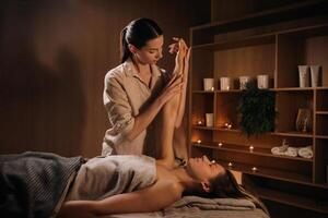 A masseuse gives a hand massage to a woman in a spa center. A professional masseur massages the hand of a girl lying in a spa center photo