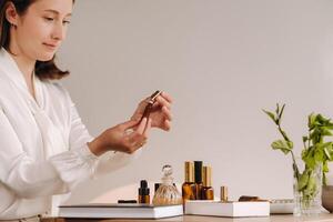 The aromatherapist girl is sitting in her office and holding a bottle of aromatic oils. there are essential oils on the table photo