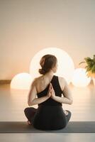 A girl in black sportswear does yoga on a mat in the fitness room photo