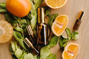 Essential oil in bottles with the aroma of orange and mint lying on a wooden surface photo
