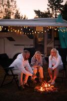 A family cooks sausages on a bonfire near their motorhome in the woods photo