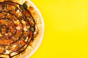 Delicious large pizza with bacon and spinach on a yellow background photo