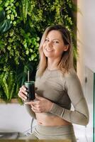 A sporty woman in sportswear holds a smoothie cocktail in her hand. The concept of healthy eating photo