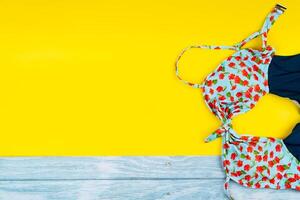 Top view of the swimsuit lying on a blue wooden and yellow background.Summer vacation concept photo