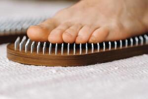 The man's feet are next to boards with nails. Yoga classes photo