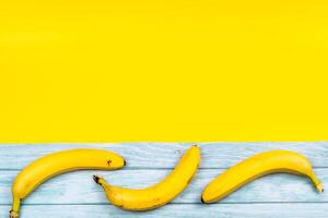 amarillo bananas mentira en un azul de madera antecedentes y un amarillo antecedentes foto