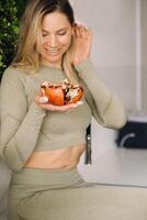 A sporty woman in sportswear holds a grenade in her hand. The concept of healthy eating photo