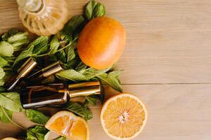 Essential oil in bottles with the aroma of orange and mint lying on a wooden surface photo