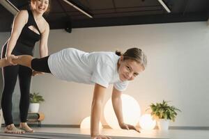 Mom and teenage daughter do gymnastics together in the fitness room. A woman and a girl train in the gym photo