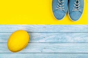 Blue shoes and a melon stand on an isolated mixed blue and yellow background photo