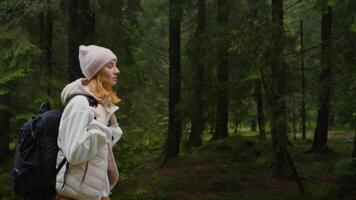 Side view of woman with backpack thoughfully walking in the forest. video