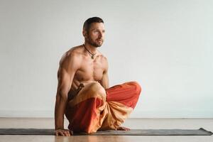 a man with a naked torso does yoga standing on his hands indoors. Fitness Trainer photo