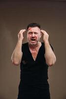 Against a gray background stands a battered angry man in a black T-shirt with wounds photo