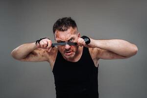 on a gray background stands a battered man in a black T shirt looking like a fighter and preparing for a fight photo