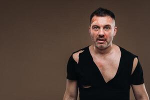 Against a gray background stands a battered angry man in a black T-shirt with wounds photo