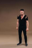 Against a gray background stands a battered angry man in a black T-shirt with wounds photo