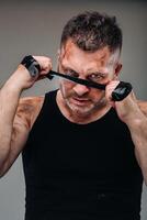 on a gray background stands a battered man in a black T shirt looking like a fighter and preparing for a fight photo