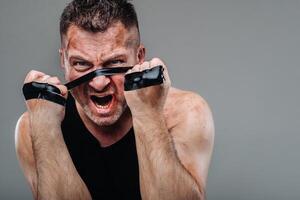 on a gray background stands a battered man in a black T shirt looking like a fighter and preparing for a fight photo