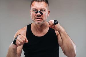 on a gray background stands a battered man in a black T shirt looking like a fighter and preparing for a fight photo