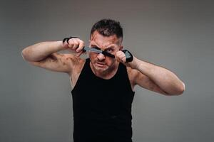 on a gray background stands a battered man in a black T shirt looking like a fighter and preparing for a fight photo