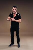 Against a gray background stands a battered angry man in a black T-shirt with wounds photo