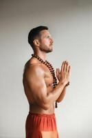 A muscular man with a bare torso and an amulet is standing in the room photo