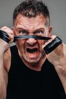 on a gray background stands a battered man in a black T shirt looking like a fighter and preparing for a fight photo