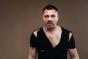 Against a gray background stands a battered angry man in a black T-shirt with wounds photo