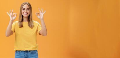 Optimistic charming woman with fair hair and no make-up in yellow t-shirt showing okay or approval gesture assuring everything ok and nothing to worry she can handle project alone, smiling confident photo