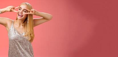 Carefree joyful beautiful fabulous blond woman having fun celebrating partying dancing happily show victory peace disco signs look aside entertained, enjoying awesome music, red background photo