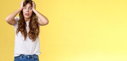 Troubled concerned anxious panicking woman female employee lose control grab head nervously stare camera frustrated scared gasping hopeless puzzled standing yellow background photo