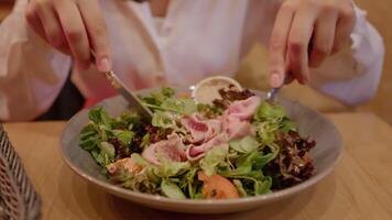 cliente miscelazione insalata utilizzando un' coltello e un' forchetta mentre mangiare fuori. video