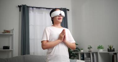 imágenes estable disparo, relajado joven mujer vestir vr gafas de protección en pie haciendo yoga disfrutando descanso en vivo habitación a hogar, respiración Fresco aire, video