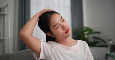 Footage dolly shot, Happy young woman is practicing yoga and stretching her neck at home with eyes closed, relaxing body and mind alone on sofa in the living room,relaxation lifestyle video