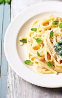 AI generated Creamy pasta with spinach and cream cheese on white rustic country wooden table, homemade easy meal recipe for lunch or dinner, generative ai photo