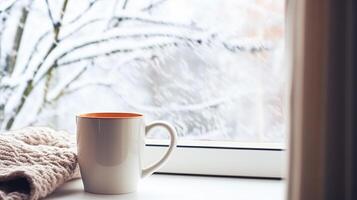 AI generated Winter holidays, calm and cosy home, cup of tea or coffee mug and knitted blanket near window in the English countryside cottage, holiday atmosphere photo