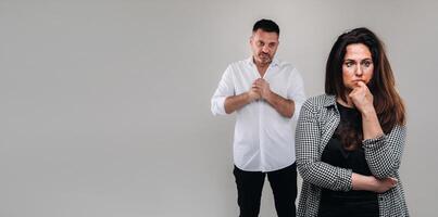 A woman beaten by a man stands on a gray background. Domestic violence photo