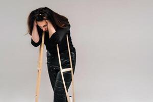 A battered woman in black clothes with casters in her hands on a gray background photo