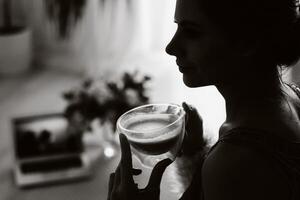 un relajado niña a hogar bebidas café y relojes un pelicula.domestica calma.la niña es sentado cómodamente en el sofá y Bebiendo cafe.negro y blanco foto